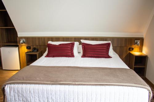 a bedroom with a large bed with red pillows at Hotel Fioreze Centro in Gramado