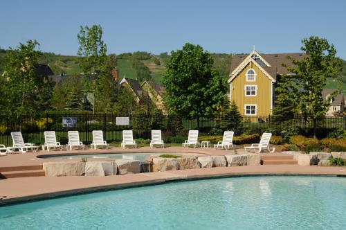 a pool with lounge chairs and a house in the background at Blue Mountain Resort Home Collection in Blue Mountains