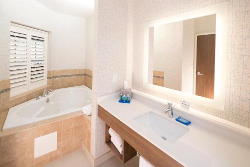 a bathroom with a tub and a sink and a mirror at Holiday Inn Express Hotel & Suites Bay City, an IHG Hotel in Bay City