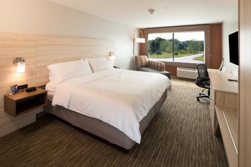 a hotel room with a bed and a desk and a window at Holiday Inn Express Hotel & Suites Bay City by IHG in Bay City