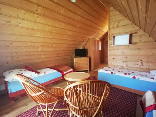 a room with two beds and a tv in a log cabin at Dom Gościnny Skalnica in Poronin