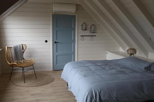 a bedroom with a bed and a chair and a door at Iris't; Dijkhuisje in de polders van Groede. in Groede