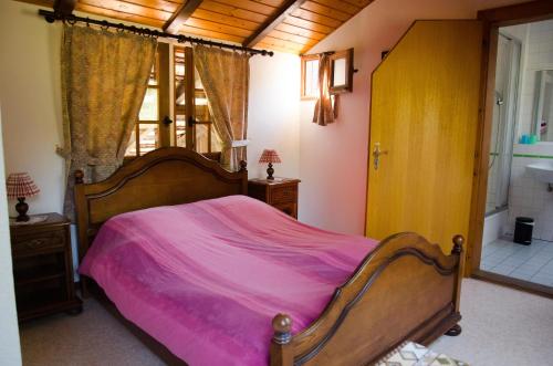 ein Schlafzimmer mit einem großen Bett mit einer rosa Decke in der Unterkunft Ferme Auberge du Moulin des Sept Fontaines in Drachenbronn
