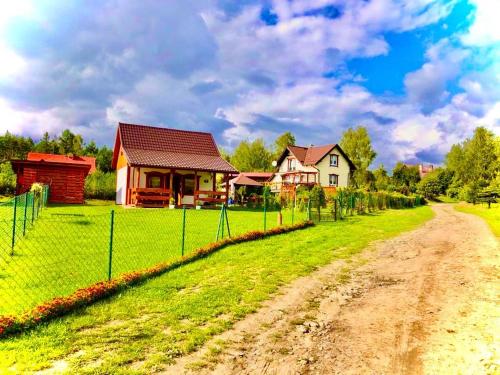 a dirt road in front of a house with a fence at Domki Eden Kaszuby balia sauna alpaki mini zoo in Gołubie