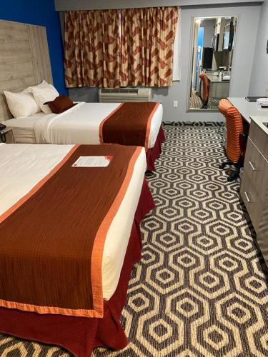 a hotel room with two beds and a mirror at Ramada by Wyndham Medicine Hat in Medicine Hat