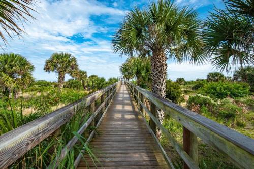 a wooden bridge with palm trees on a beach at Driftwood Escape in Saint Augustine Beach