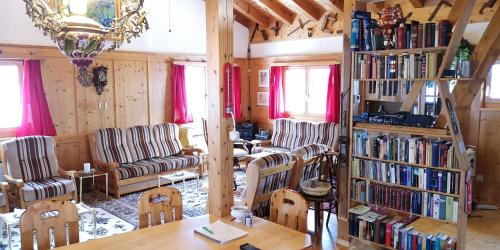 a living room with a table and chairs and bookshelves at grosses Ferienhaus mit Sauna im Skigeb. Obersaxen in Obersaxen