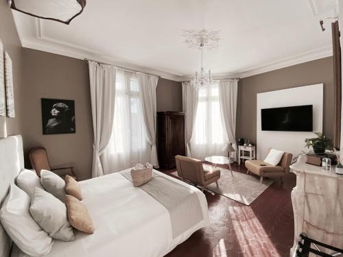 a bedroom with a large white bed and a living room at La Domitia - Maison d'hôtes, spa & massages in Montbazin