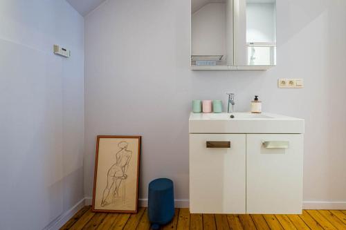 a white kitchen with a sink and a picture on the floor at Villa Louise Oostende in Ostend