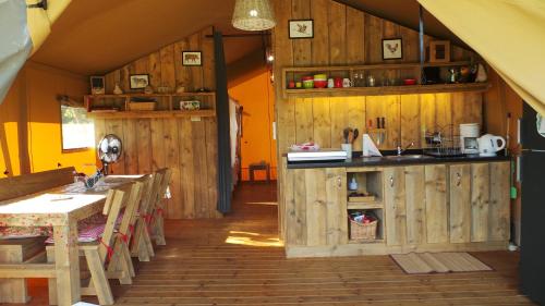 a kitchen with wooden walls and wooden tables and chairs at Retour Au Source in Monprimblanc