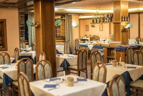 un comedor con mesas y sillas con servilletas azules en Hotel Quadrifoglio en Pinzolo