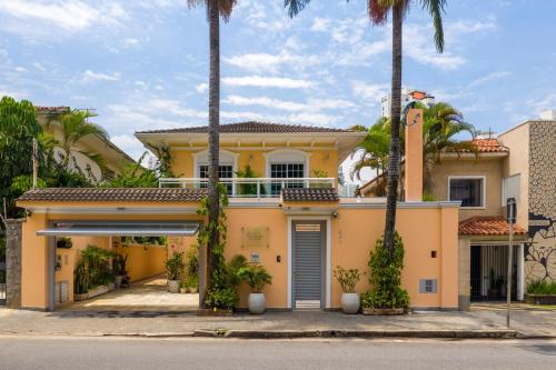 a yellow house with palm trees in front of it at Hotel Pousada Pacaembu in Sao Paulo