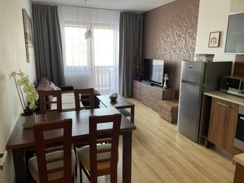 eine Küche und ein Wohnzimmer mit einem Tisch und einem Kühlschrank in der Unterkunft ApartmanTatryView in Veľká Lomnica