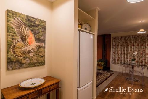 a painting of a bird on a wall next to a refrigerator at Night Sky Cottages - Kea Cottage - LUXURY in Twizel
