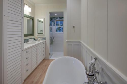 a white bathroom with a tub and a sink at Gorgeous Renovated 1937 Plantation Style Beach House 50 Steps to the Center of the Beach home in Kailua