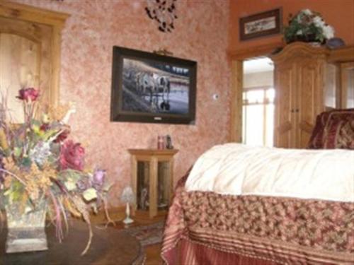 a bedroom with a bed and a tv on the wall at River's Bend Lodge in Cascade
