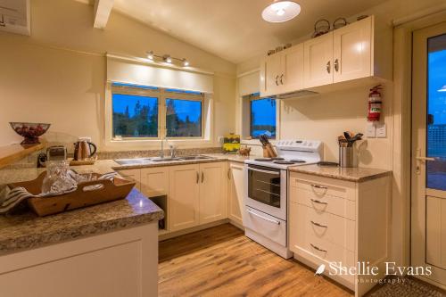 a kitchen with white cabinets and white appliances at Night Sky Cottage - Kahu Cottage - HOT TUB in Twizel