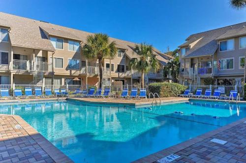 a swimming pool with blue chairs and condos at Walk to Hilton Head Island Beach Villa with Balcony in Hilton Head Island