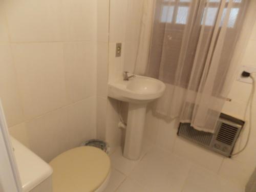 Baño blanco con aseo y lavamanos en A meson Suites en Salvador
