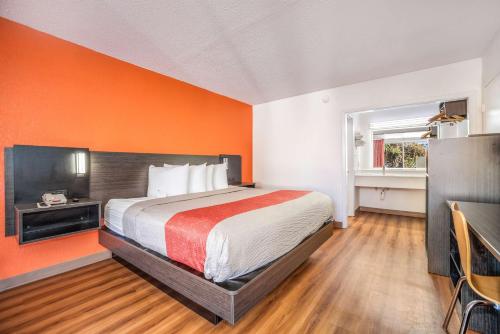 a bedroom with a bed and an orange wall at Motel 6-Florence, SC in Florence