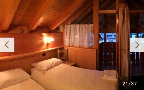 a bedroom with two beds in a wooden room at Locanda Rondolost in Cencenighe