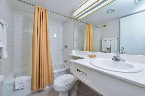 uma casa de banho branca com um lavatório e um WC em Travelodge by Wyndham Cleveland Airport em Brook Park