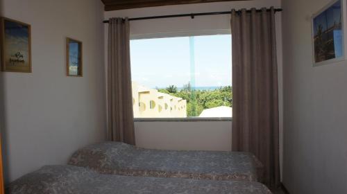 um quarto com uma cama e uma grande janela em Imbassai Summer Flats Village em Imbassaí