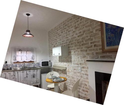 a kitchen with a table and a brick wall at Ville France - Chalé Côte d'Azur a 5 min do Centro in Camanducaia