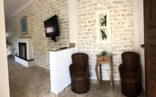a living room with a brick wall with two chairs and a tv at Ville France - Chalé Côte d'Azur a 5 min do Centro in Camanducaia