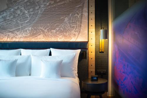 a bedroom with a large bed with white pillows at Hotel Indigo Phuket Patong by IHG in Patong Beach