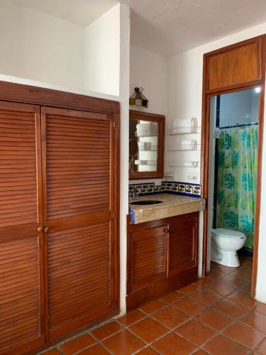 a bathroom with a toilet and a wooden door at Vallarta Jr Suites in Puerto Vallarta