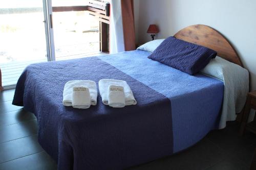 ein Schlafzimmer mit einem blauen Bett und Hausschuhen darauf in der Unterkunft Koe Porá in Punta Del Diablo