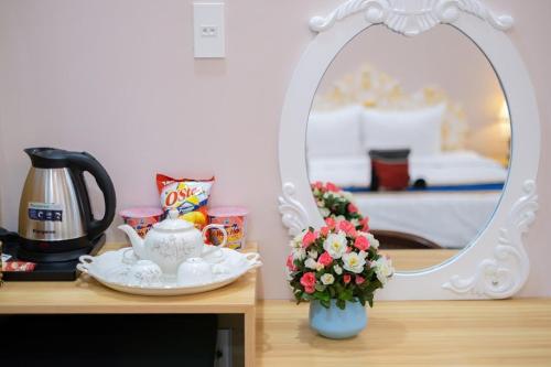 a table with a mirror and a vase with flowers on it at Quoc Vinh Hotel in Rach Gia