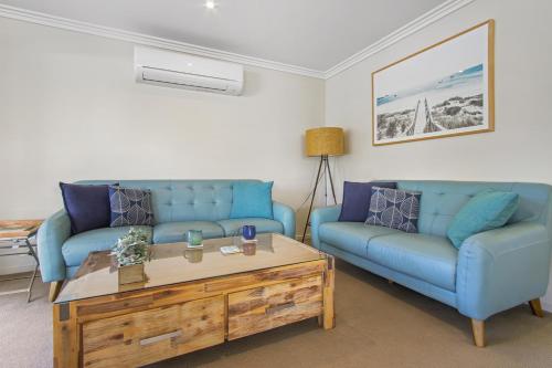 a living room with two blue couches and a coffee table at McMillans of Metung Coastal Resort in Metung