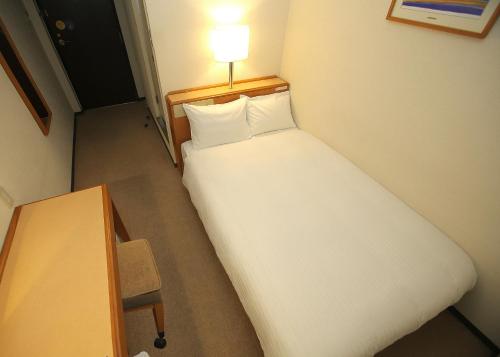 a bed in a room with a lamp on top of it at Smile Hotel Fukuoka Okawa in Ōkawa