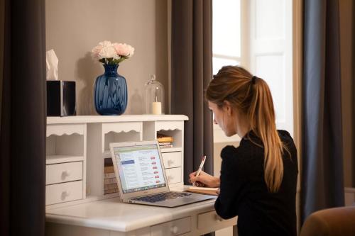 a woman sitting at a desk with a laptop computer at Les chambres chez Grand-mère à Chambéry in Chambéry