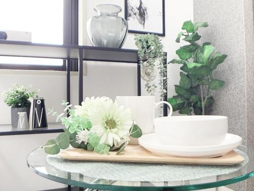 a glass table with a plate and flowers on it at OUCHI HOTEL Takaramachi in Hiroshima
