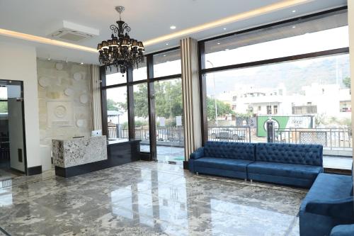 a living room with a blue couch and large windows at Clover Inn in Udaipur