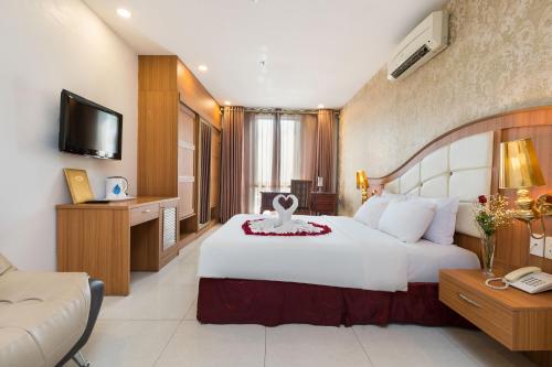 a hotel room with a large white bed and a television at Lam Kinh Hotel in Ho Chi Minh City