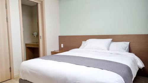 a bedroom with a large white bed with a wooden headboard at Hi Jeju Hotel in Jeju