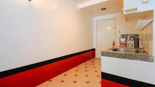 a kitchen with a sink and a red stripe at RedDoorz at The Providence Tower in Manila