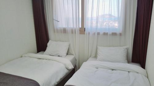 two beds in a small room with a window at Hi Jeju Hotel in Jeju