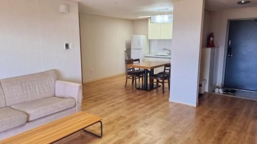 a living room and kitchen with a couch and a table at Hi Jeju Hotel in Jeju