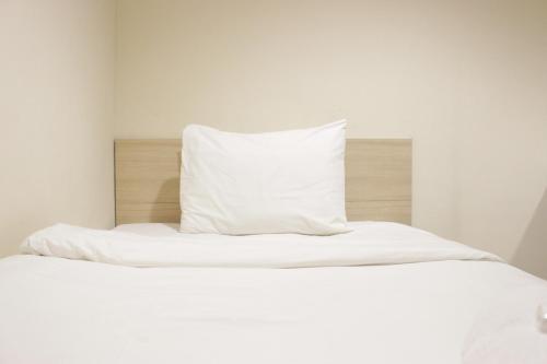 Best Location 2BR Tamansari La Grande Apartment By Travelio في باندونغ: سرير ابيض عليه مخده
