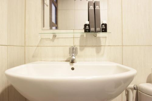 Best Location 2BR Tamansari La Grande Apartment By Travelio في باندونغ: بالوعة بيضاء في الحمام مع مرآة