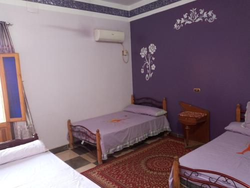 2 camas en una habitación con paredes moradas en Labib Guest House en Asuán