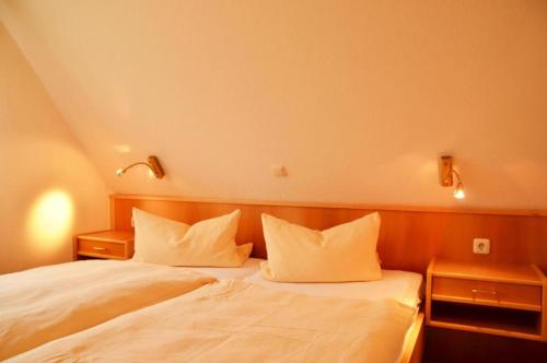 a bedroom with a bed with white sheets and pillows at Landhaus Braband Ferienhaus - Rugenbargsweg 23 in Cuxhaven