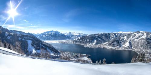 a view of a lake in the mountains with snow at Apartmenthaus Gotthardt in Kaprun