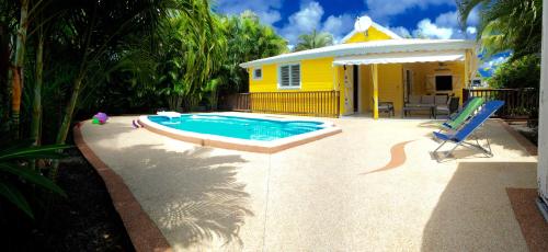 a yellow house with a swimming pool in front of it at La Villa Madinina in Les Trois-Îlets