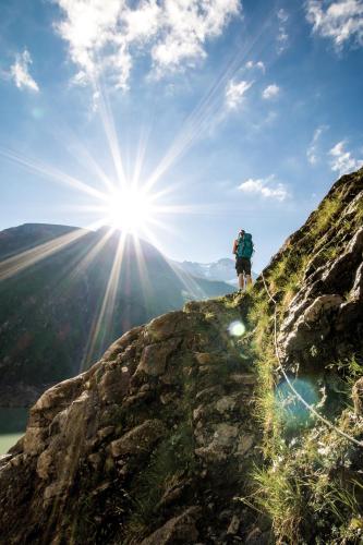 a person standing on top of a mountain with the sun at Apartmenthaus Gotthardt in Kaprun